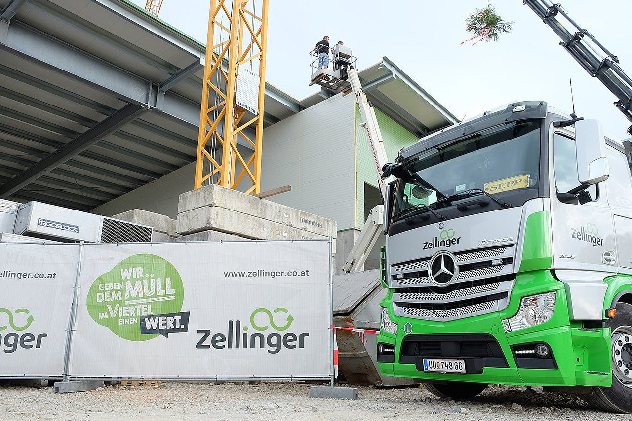 Construction site with a green and white truck, crane, and building.