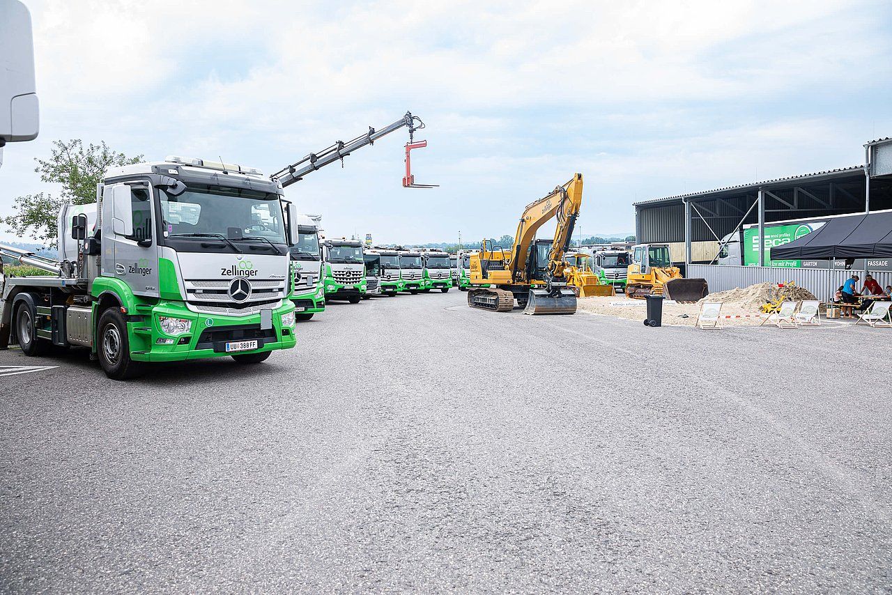 Trucks and construction equipment parked on gravel; green and silver accents.