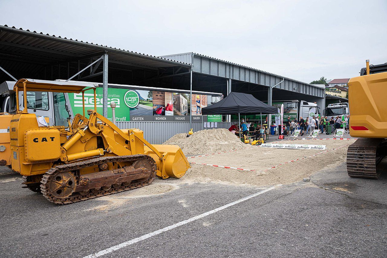 Yellow bulldozer and other construction equipment on display at an outdoor event.