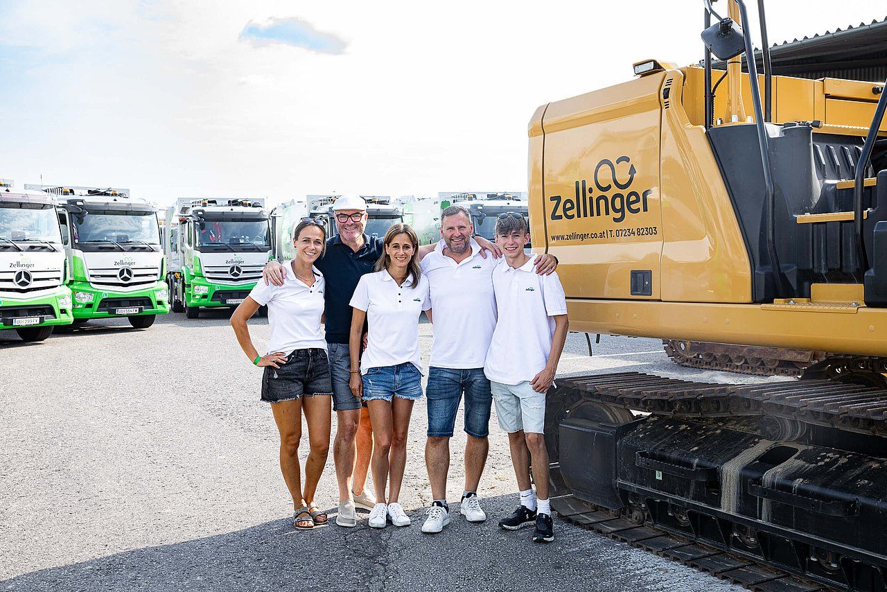 Family poses with trucks and construction equipment.