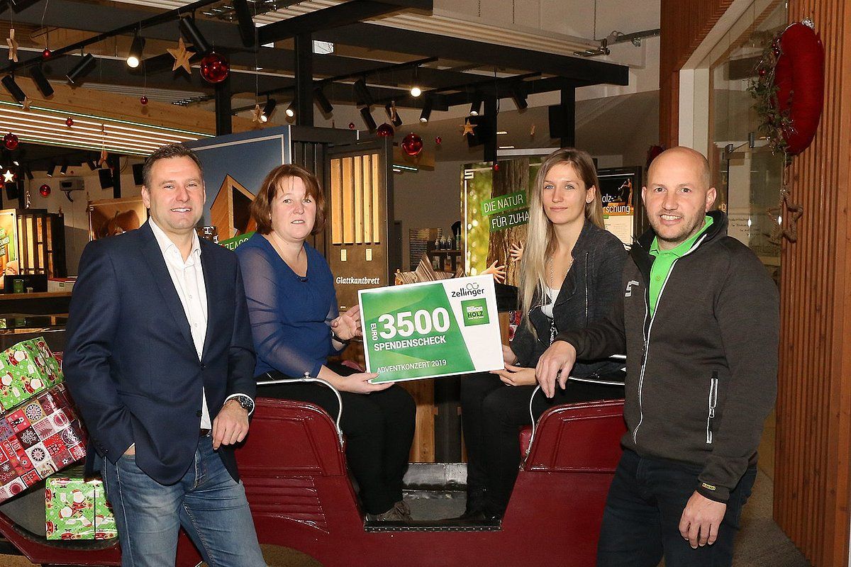 Four people holding a large check, in a decorated store, smiling.