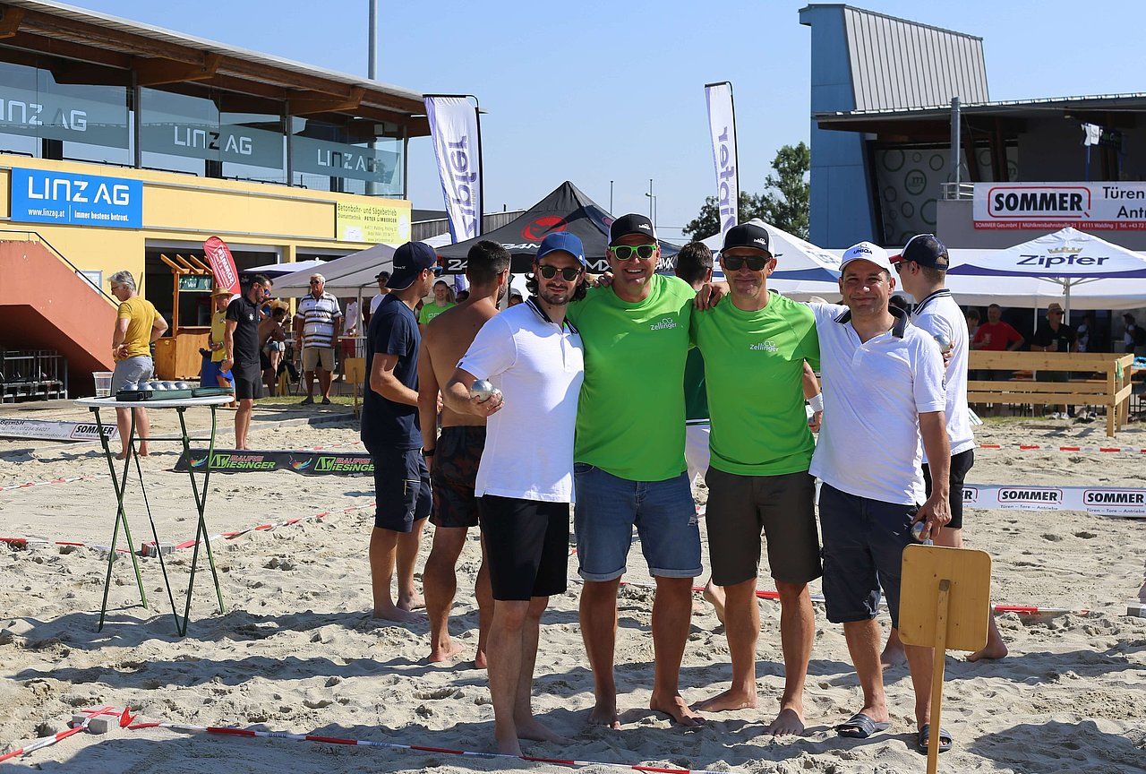 Group of friends on a sandy beach, posing with arms around each other, sunny day.