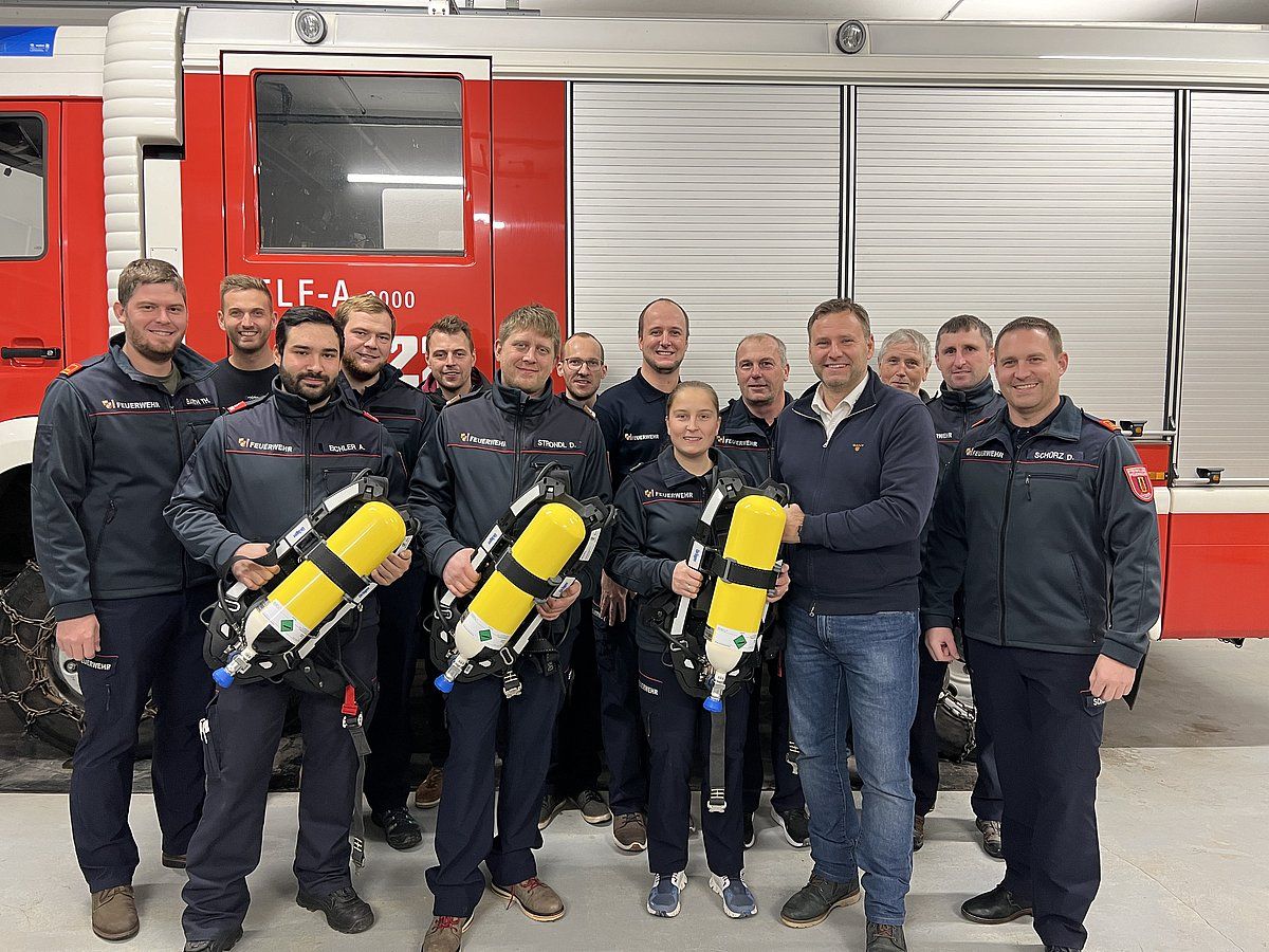 Firefighters posing with new equipment in front of a red fire truck.