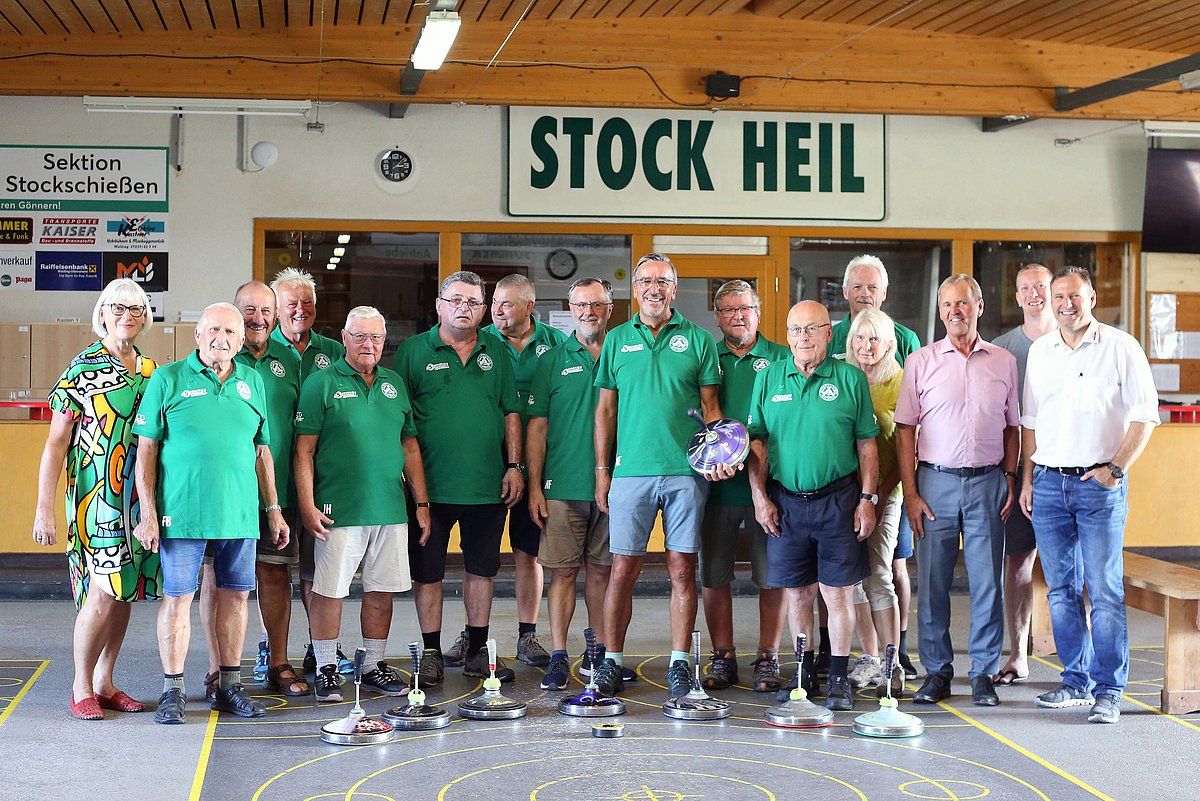 Group of men in green shirts pose in front of