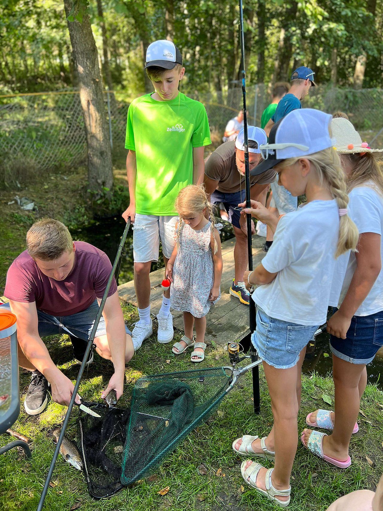 Group of kids fishing outdoors, one boy is cleaning the net, others are watching and helping.