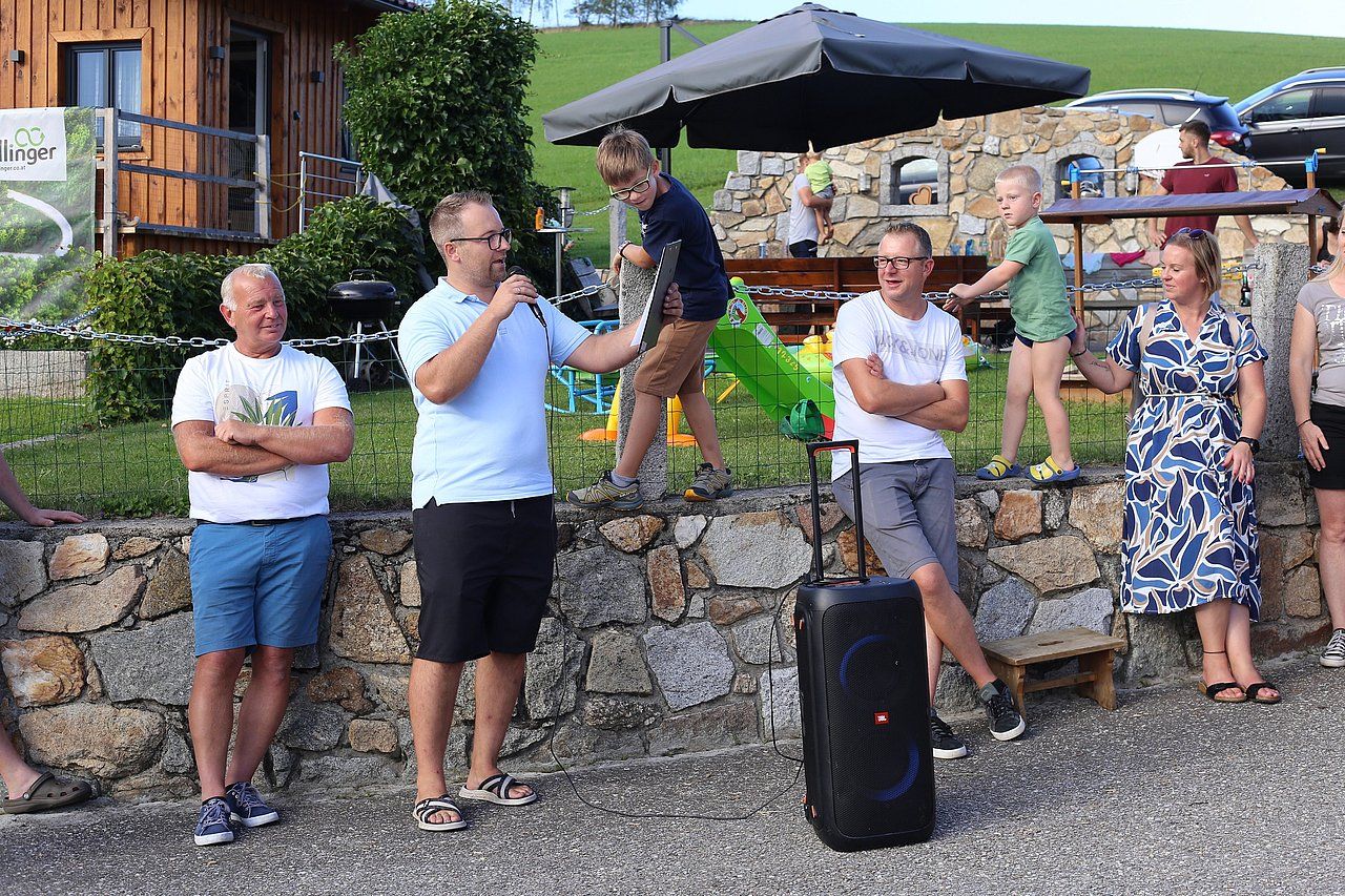 A group of people outside, with a man speaking into a microphone.