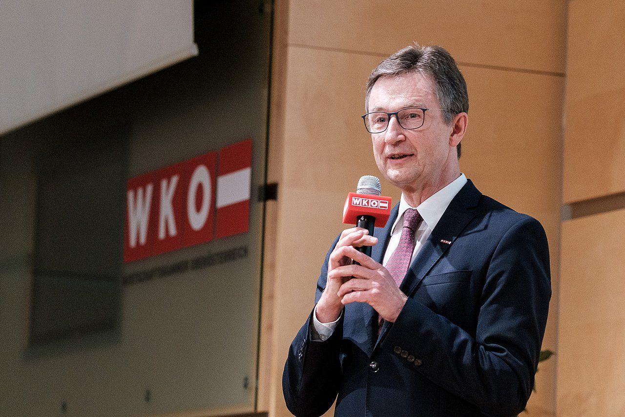 Man in suit speaking into a microphone indoors with 