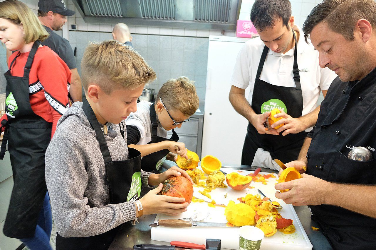 People carving pumpkins at a workshop in a kitchen.