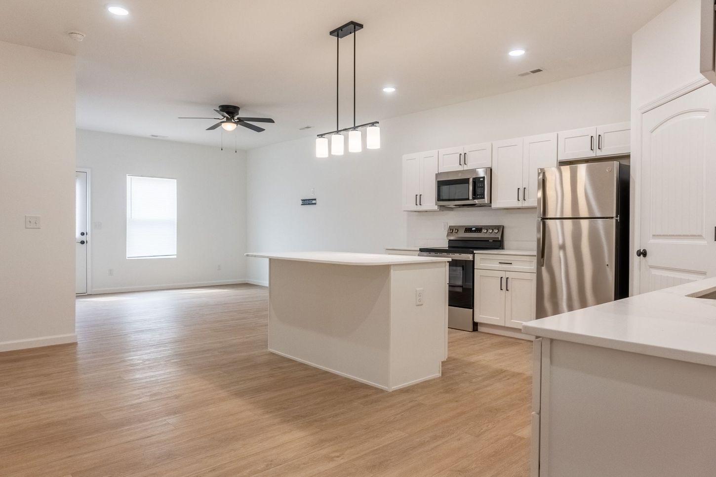 Bright, modern kitchen with white cabinets, stainless appliances, island, and wood floors