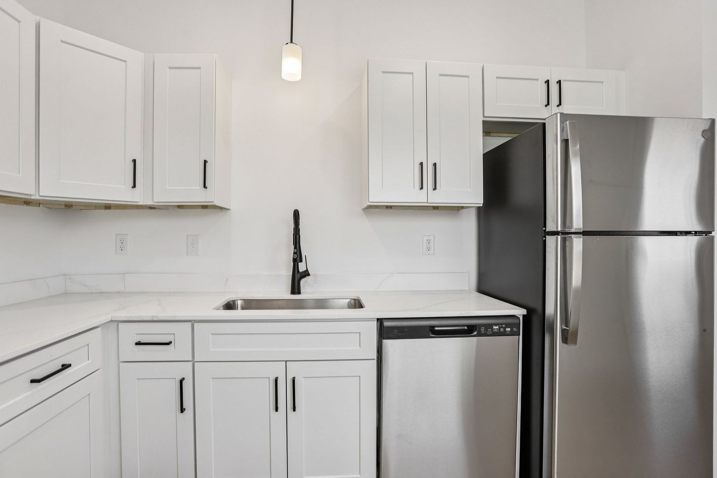 Bright white kitchen with stainless steel refrigerator, dishwasher, sink, and cabinets