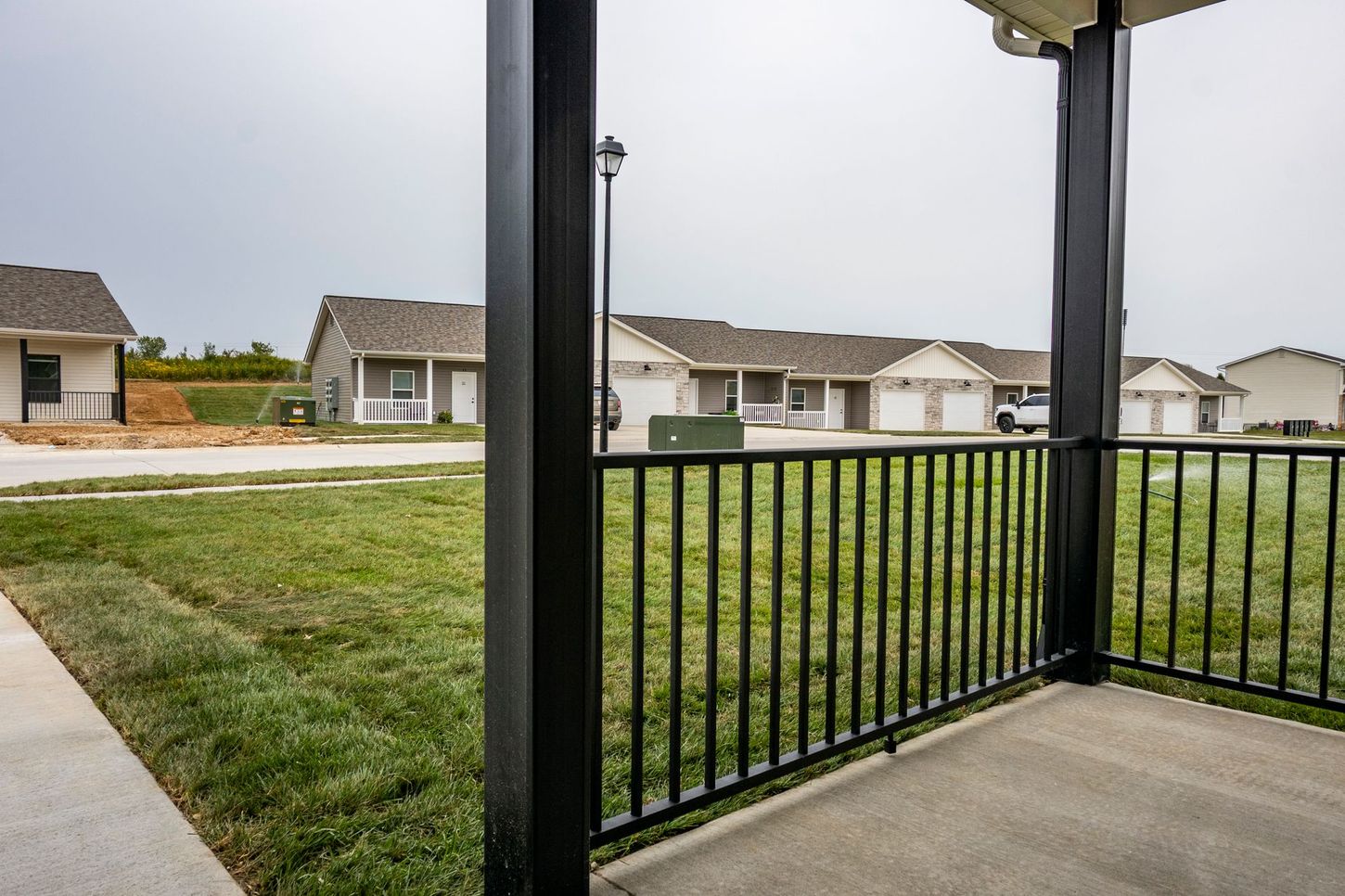 Covered porch overlooking a grassy lawn and suburban houses across the street