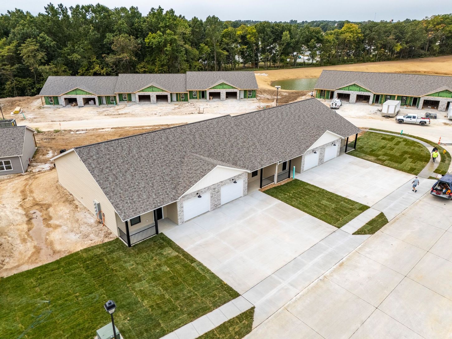 Aerial view of a row of newly built gray-roofed houses with driveways in a suburban neighborhood.