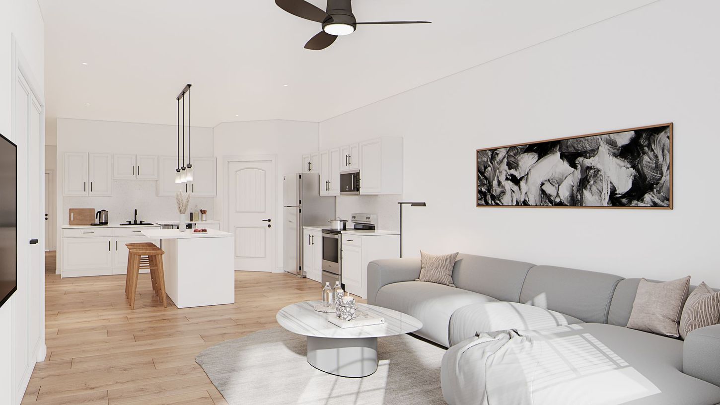 Bright open-plan living room with gray sofa, white kitchen, wood floor, and abstract wall art