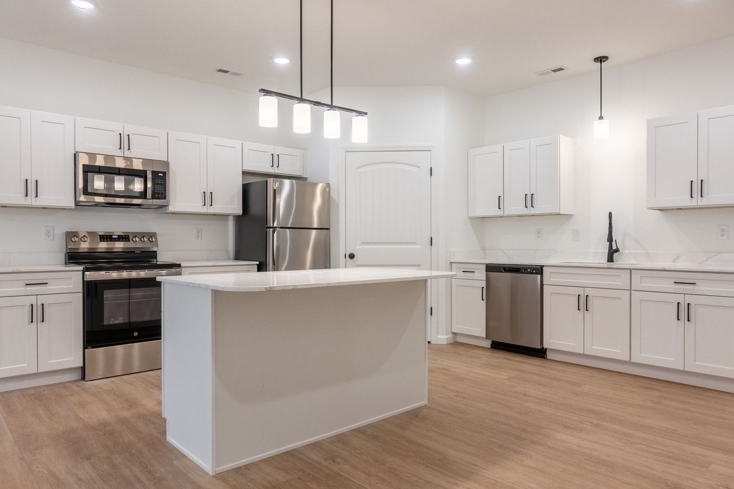 Bright modern kitchen with white cabinets, stainless steel appliances, and a large island
