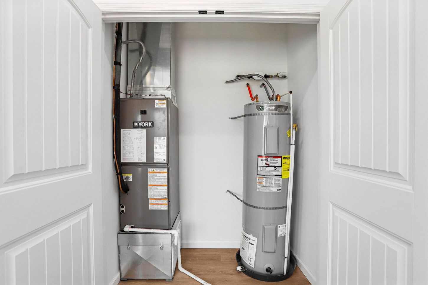 Open closet with a furnace on the left and a water heater on the right in a utility room