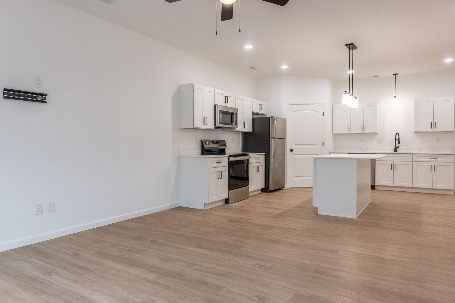 Bright white modern kitchen with island, stainless appliances, and wood flooring in an open room