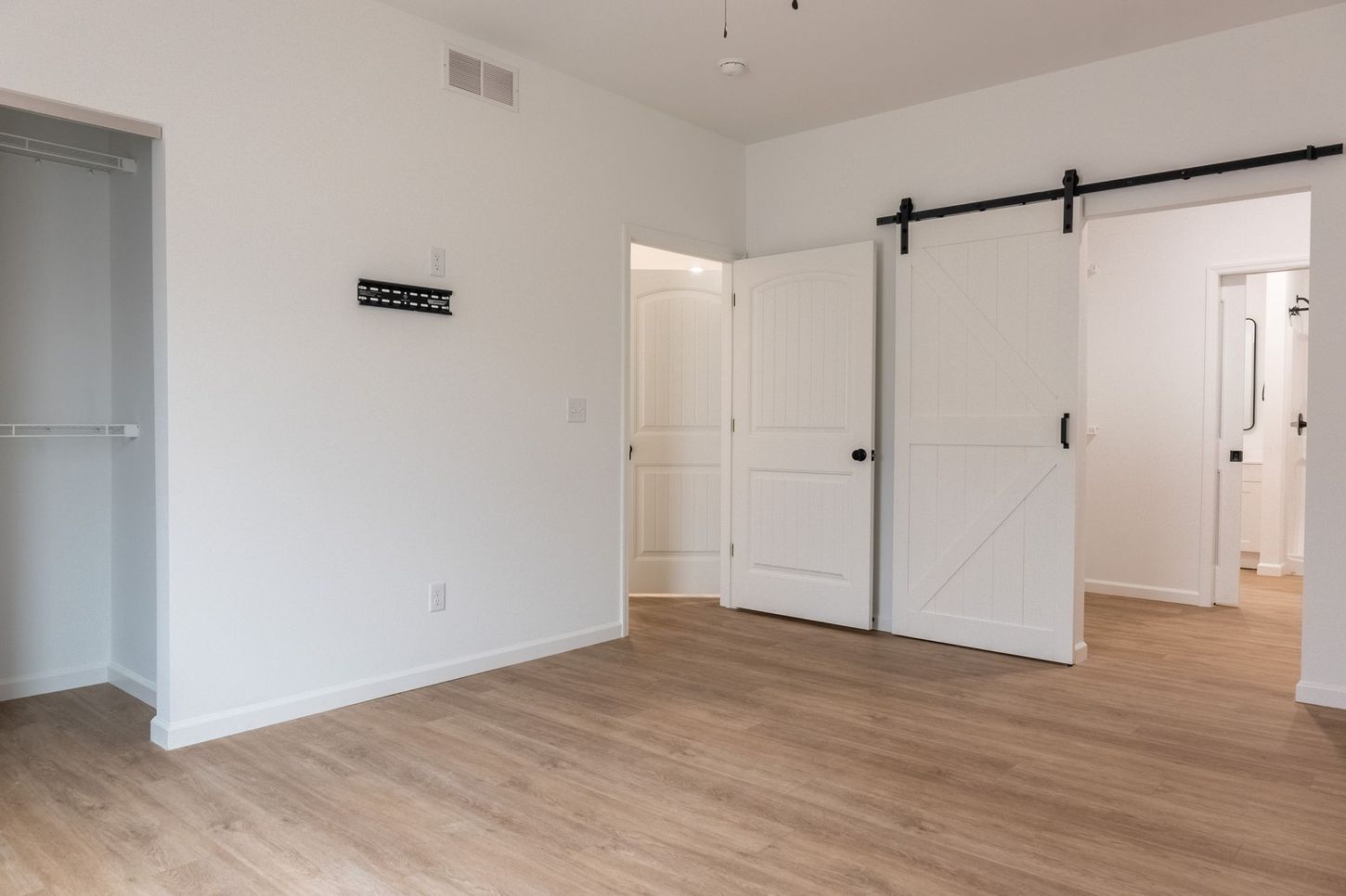 Empty white room with wood floors and a black sliding barn door.