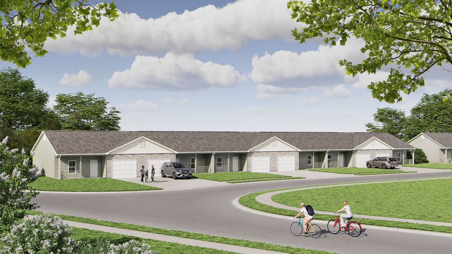 Suburban apartment complex with curving driveway, parked cars, and people walking along a landscaped path