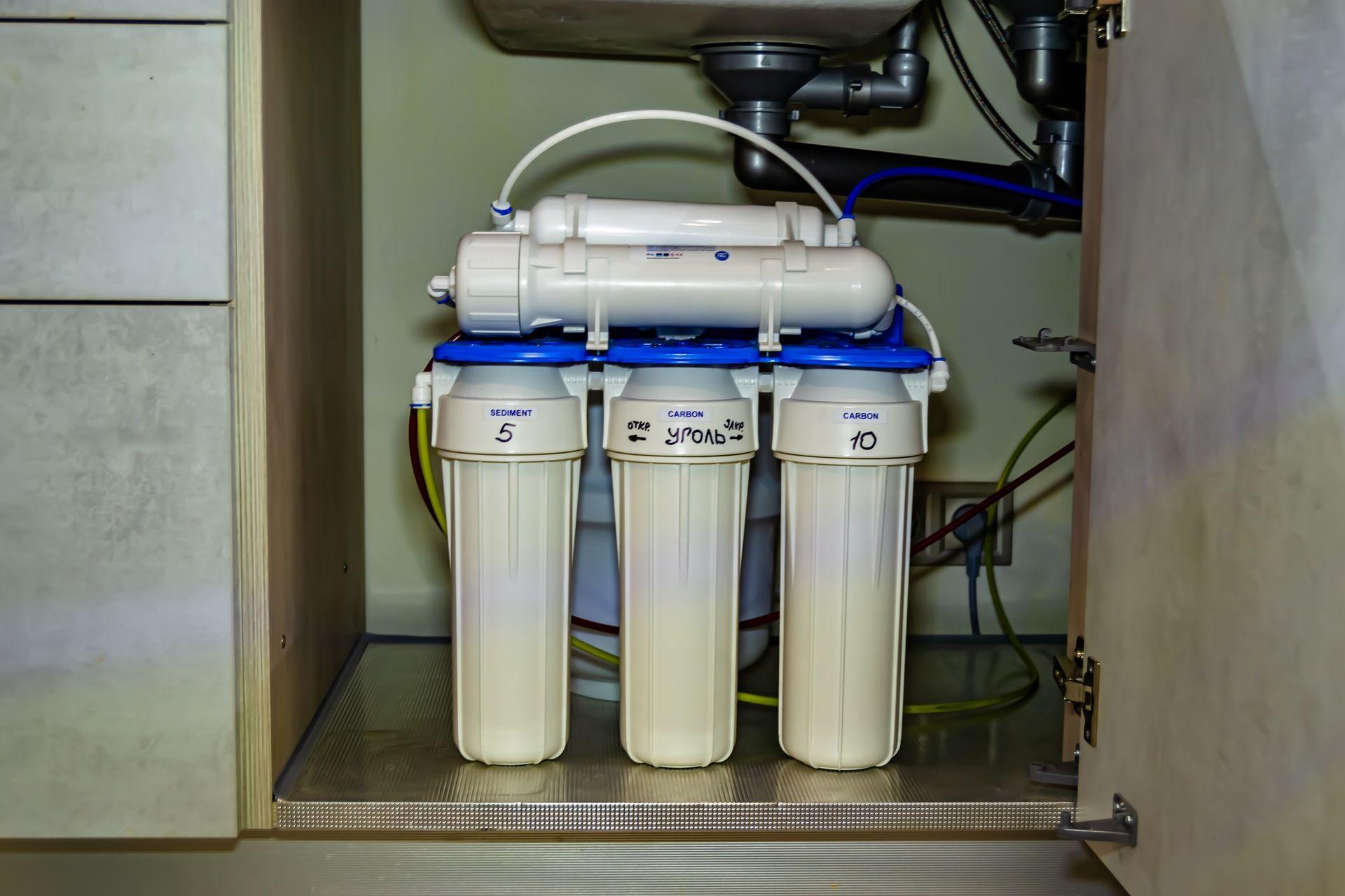 Blue water filter canisters with a pressure gauge and labeled dates.