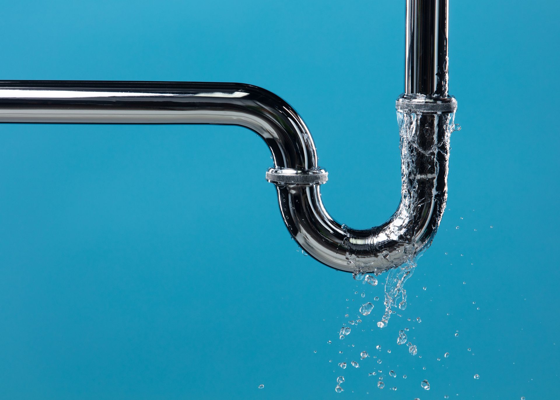 Leaking chrome pipe with water drops against a bright blue background.