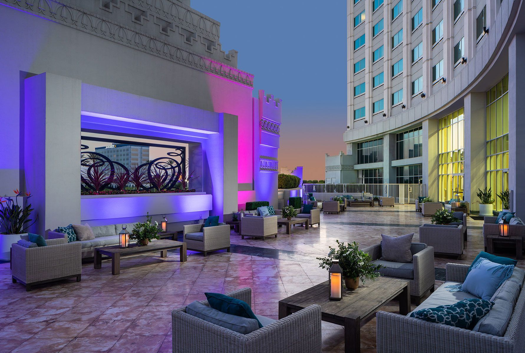 Rooftop patio with seating, lit with purple and blue lights. A building is visible in the background.