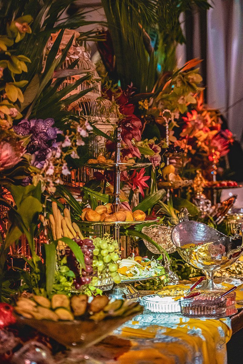 Elegant buffet with treats and flowers, various colors, ornate platters.
