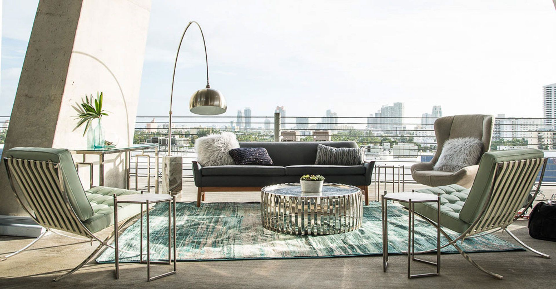 Outdoor living space with sofa, armchairs, and city skyline view.