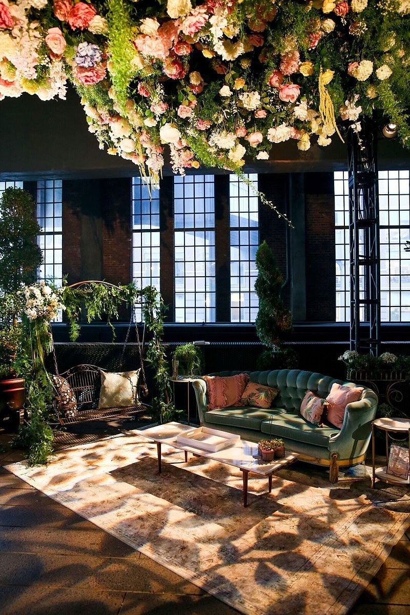 Living room with ornate ceiling flowers, velvet sofa, and tall windows. Soft lighting.