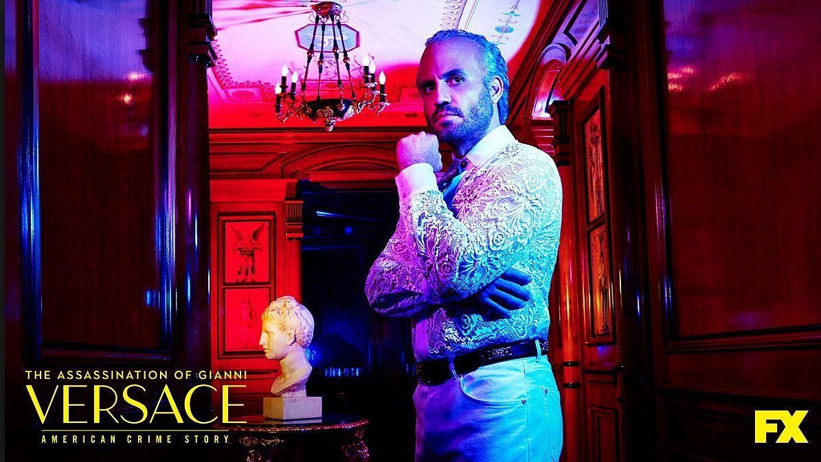 Man in sparkly shirt poses in ornate hallway, 
