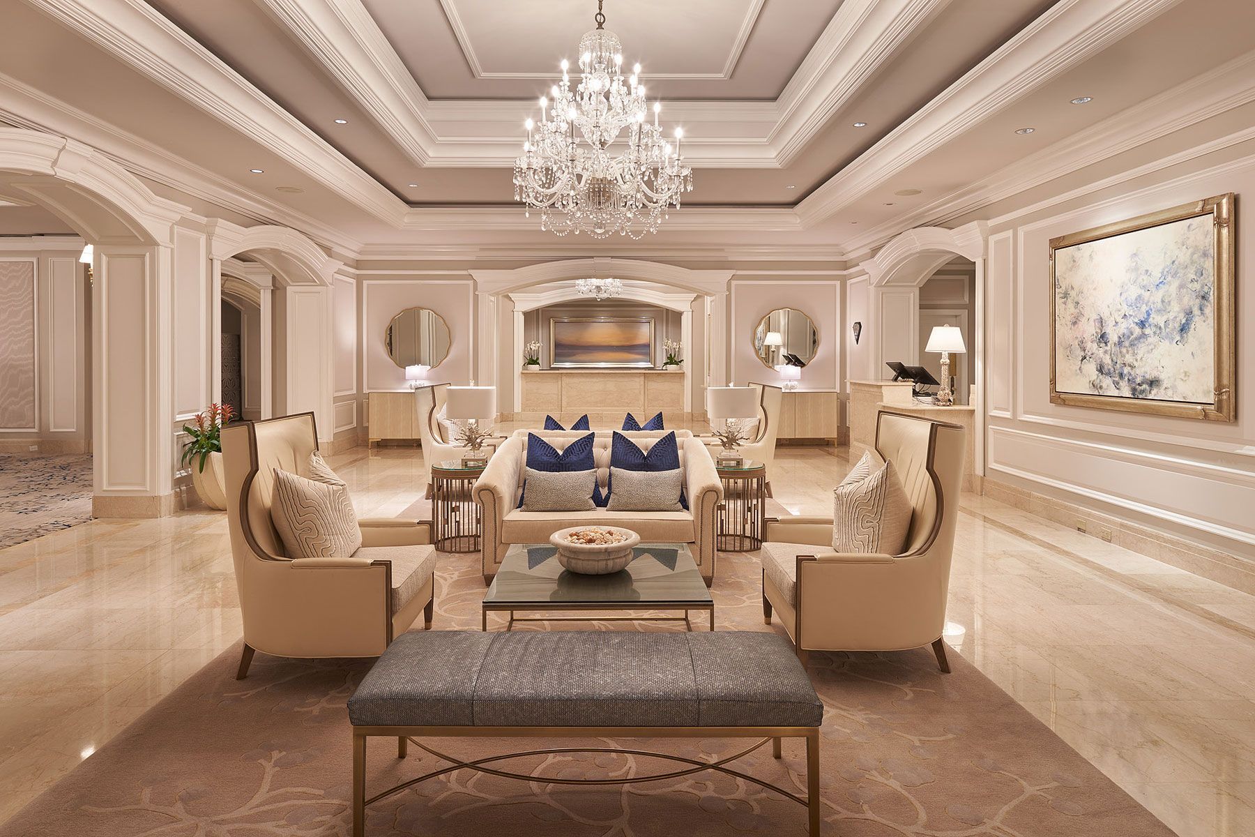 Elegant hotel lobby with chandelier, seating area, and front desk.