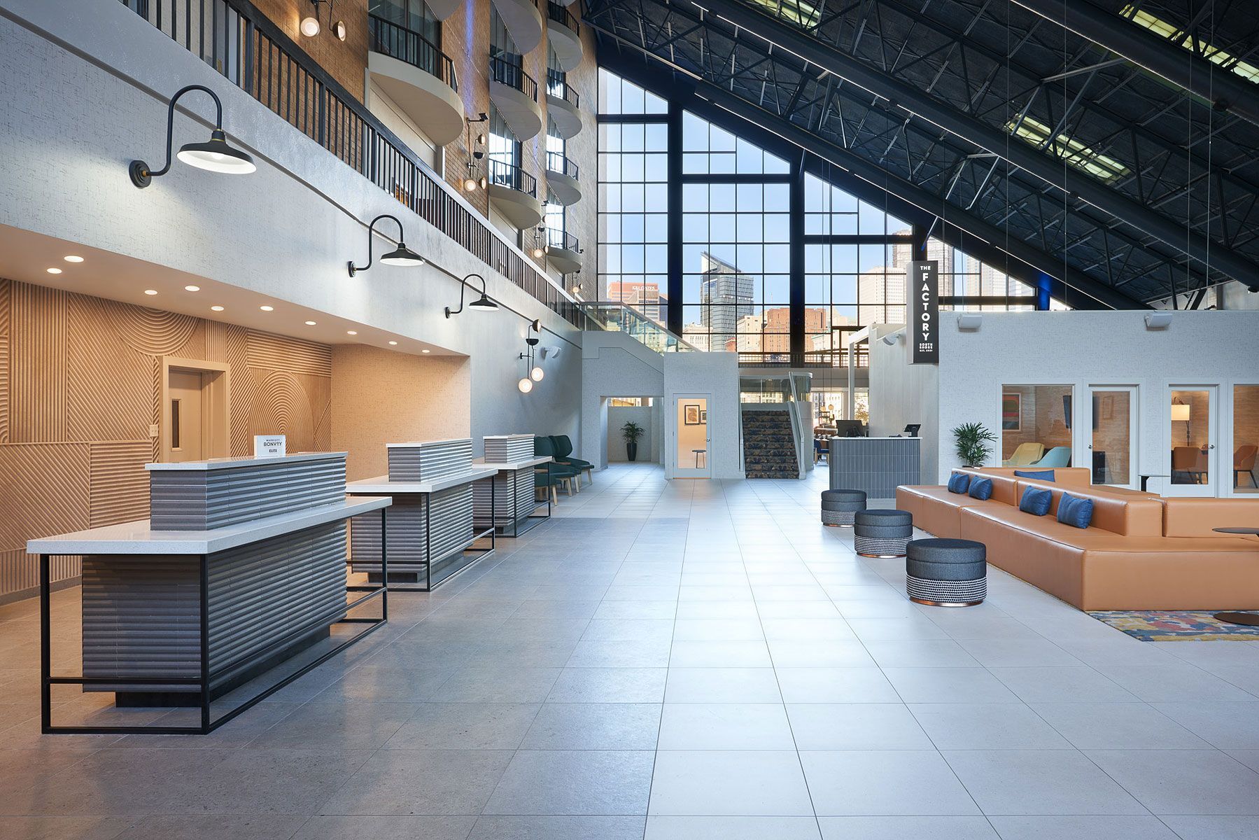Hotel lobby with check-in desks, seating, large windows, and a high ceiling.