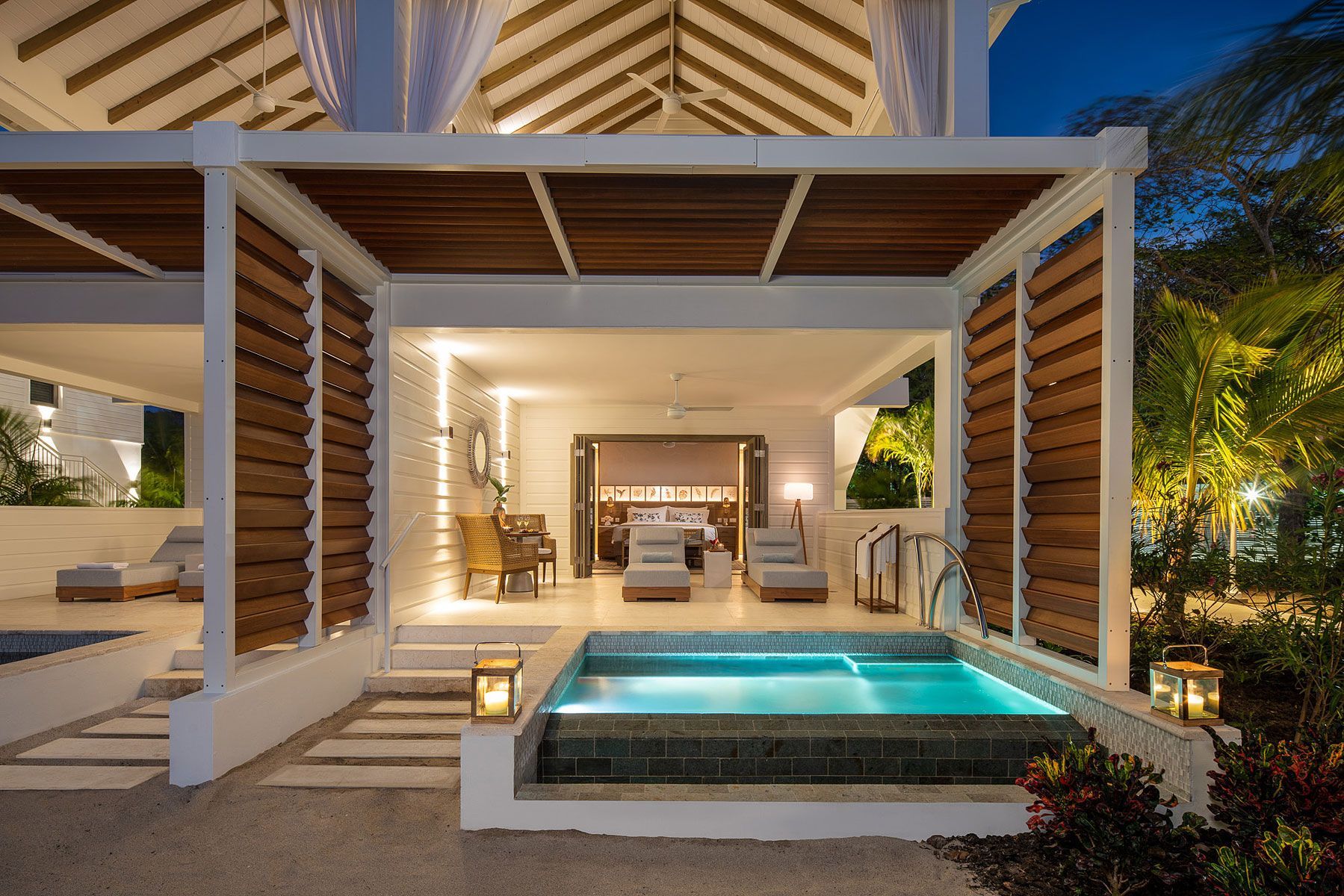 Outdoor luxury suite with small pool, white walls, wooden accents, and soft lighting at dusk.