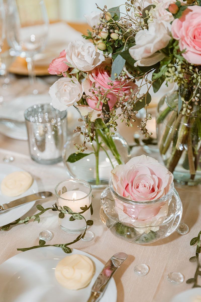 Elegant table setting with pink and white flowers, candles, and glassware.