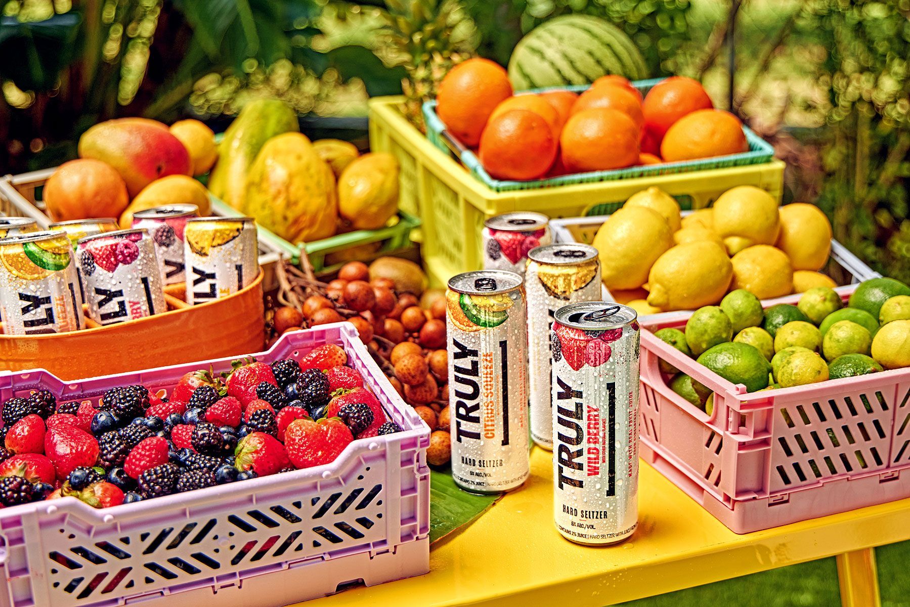 Truly hard seltzer cans surrounded by fresh fruit in colorful crates.