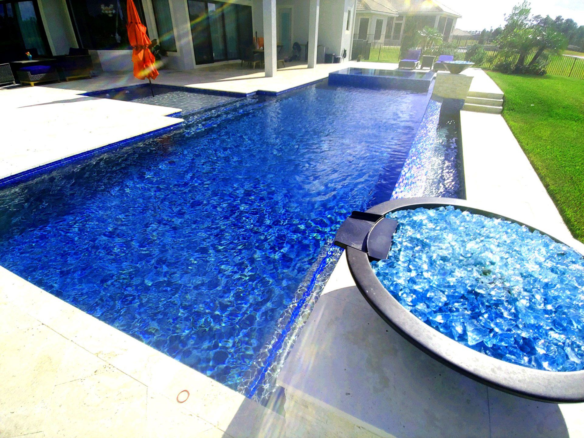 Long rectangular pool with vibrant blue tile, connected to a spa with blue glass.