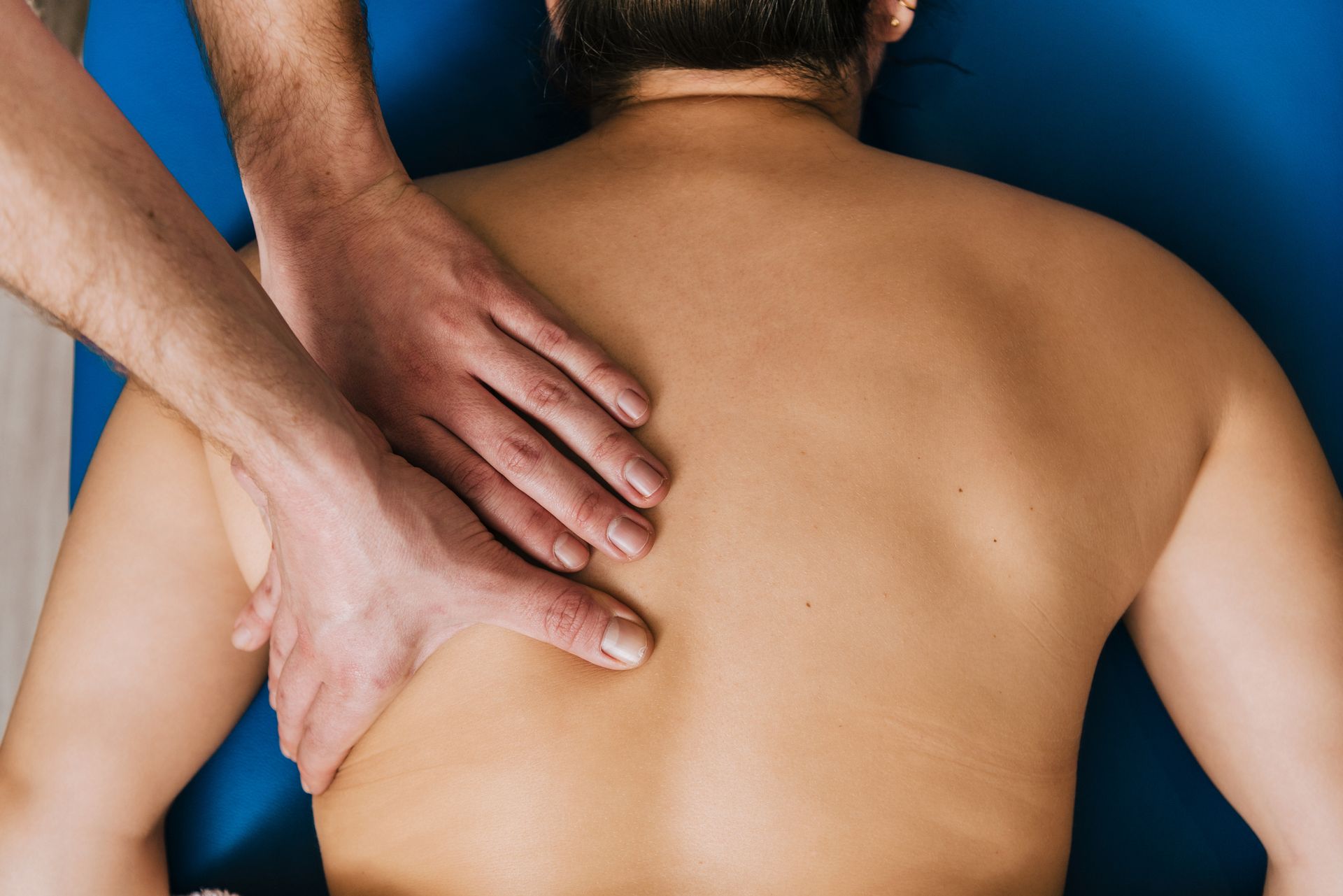 Therapist providing rehabilitation services with manual back massage on patient’s spine.