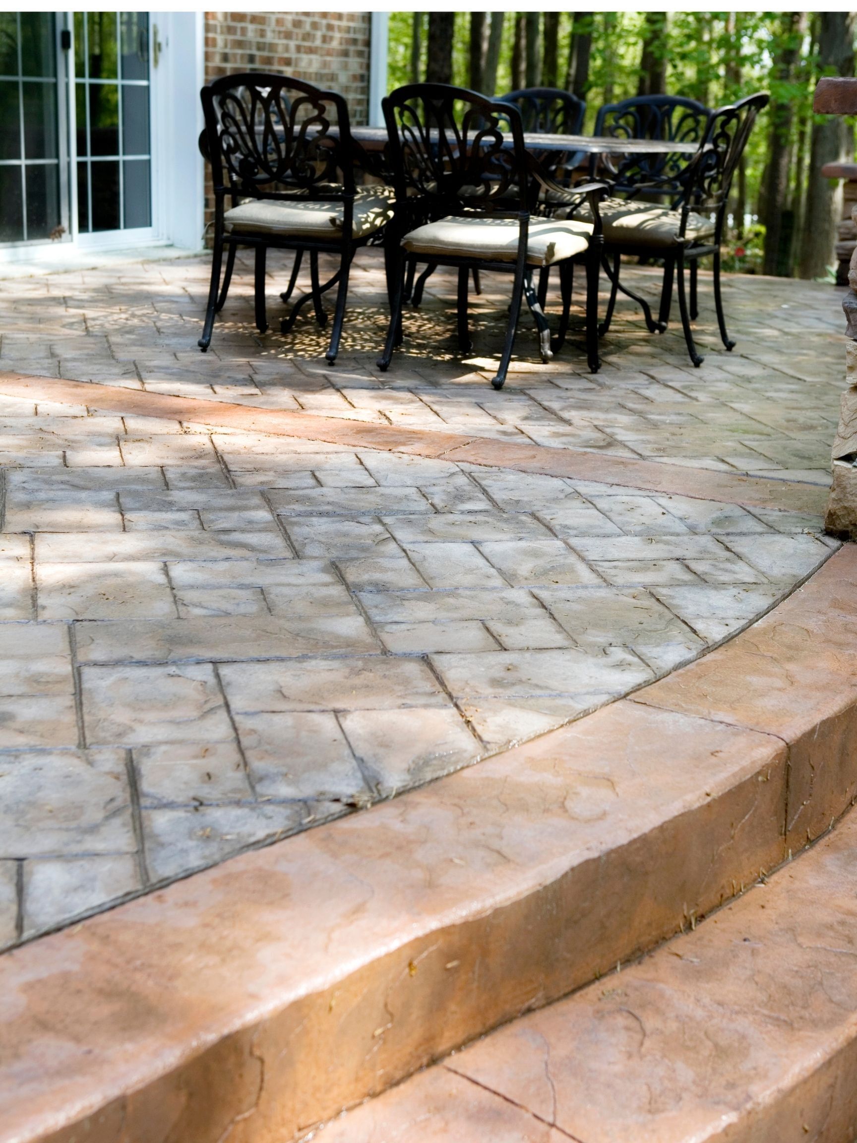 concrete patio in the back yard with table and chairs on top