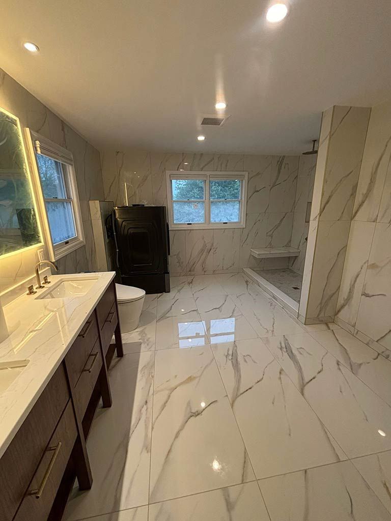 Modern bathroom with marble tile floor, vanity sink, and windowed shower area