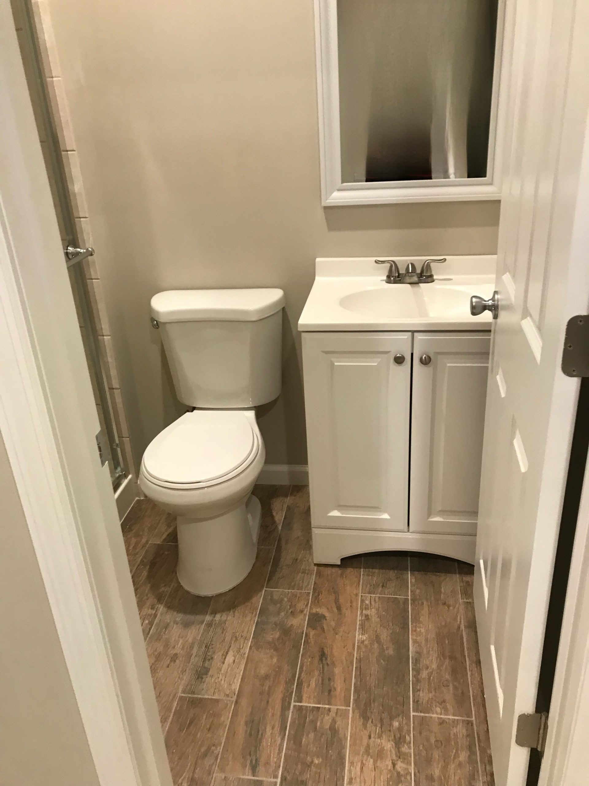 Small bathroom with toilet, white vanity sink, and wood-look floor.