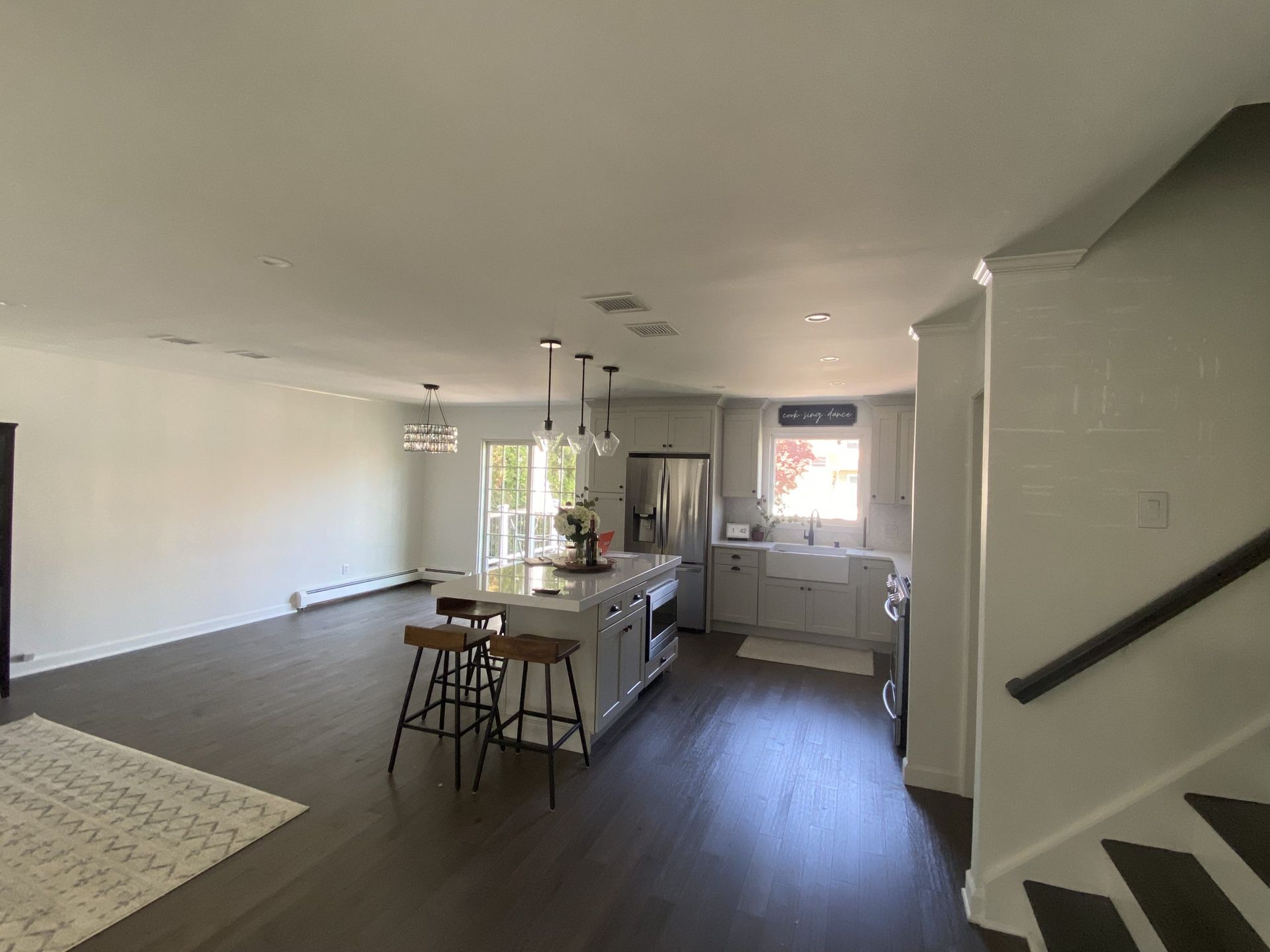 Open-plan living room and kitchen with island, bar stools, and stairs in a bright, modern home