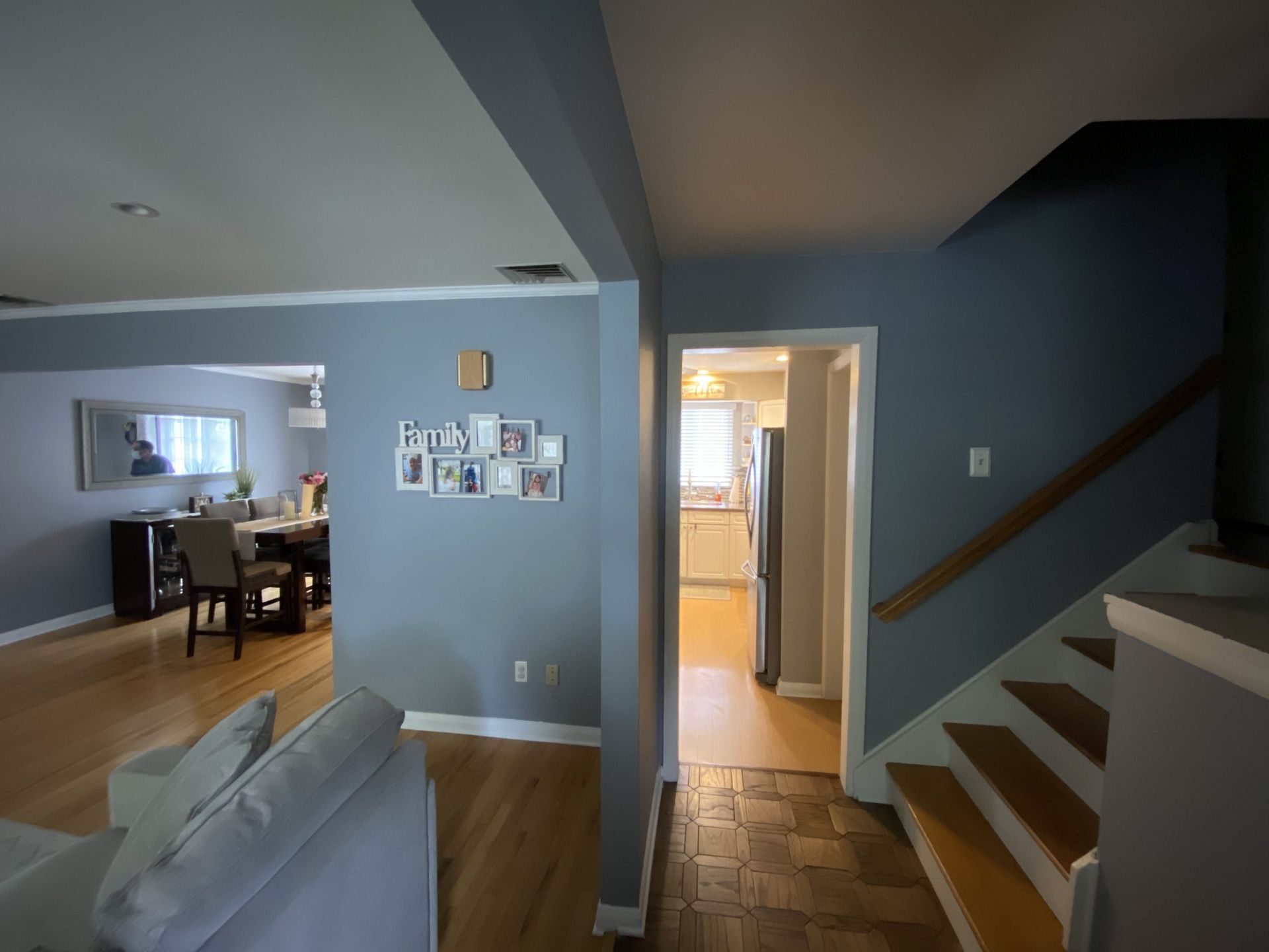 Living room with staircase, hallway, and open kitchen doorway in a gray and wood-toned home