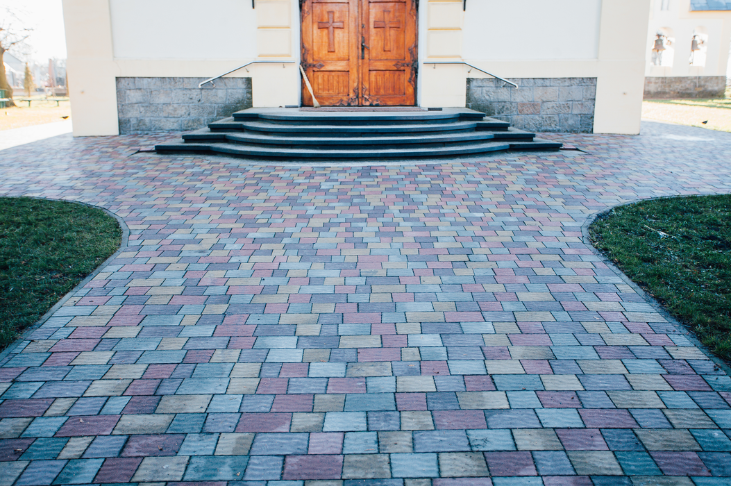 Brick walkway leading to wooden double doors with stone steps at a building entrance