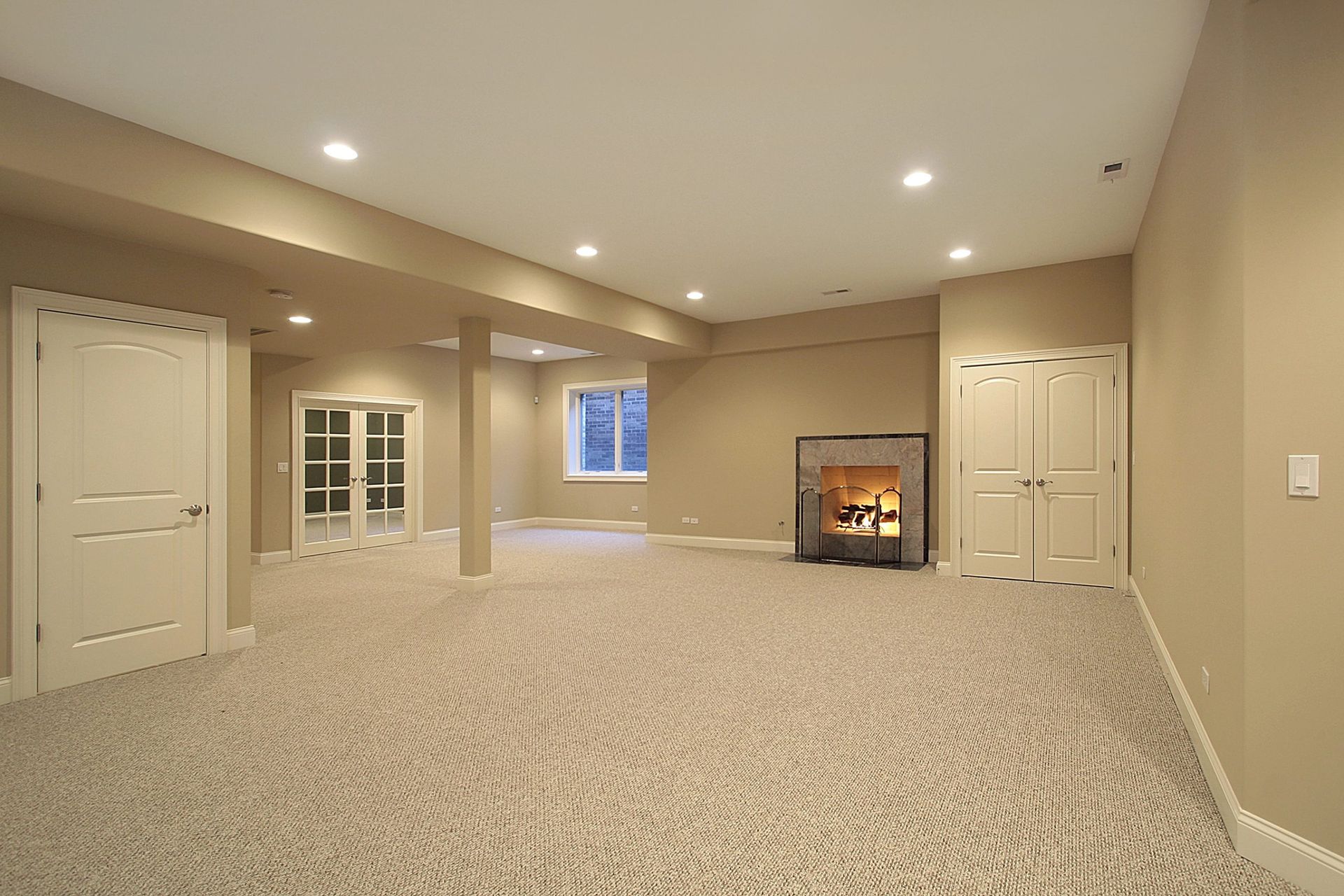 Spacious beige finished basement with carpet, recessed lights, French doors, and a fireplace alcove
