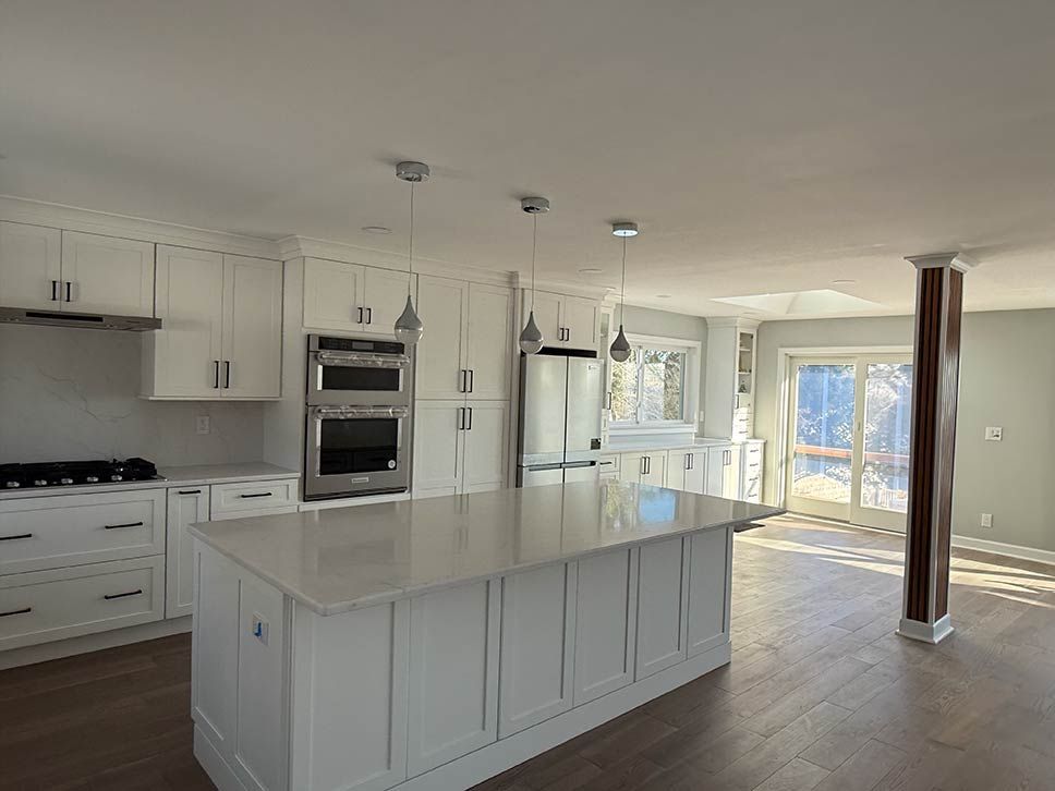 Bright white kitchen with island, stainless appliances, and open view to sunlit dining area