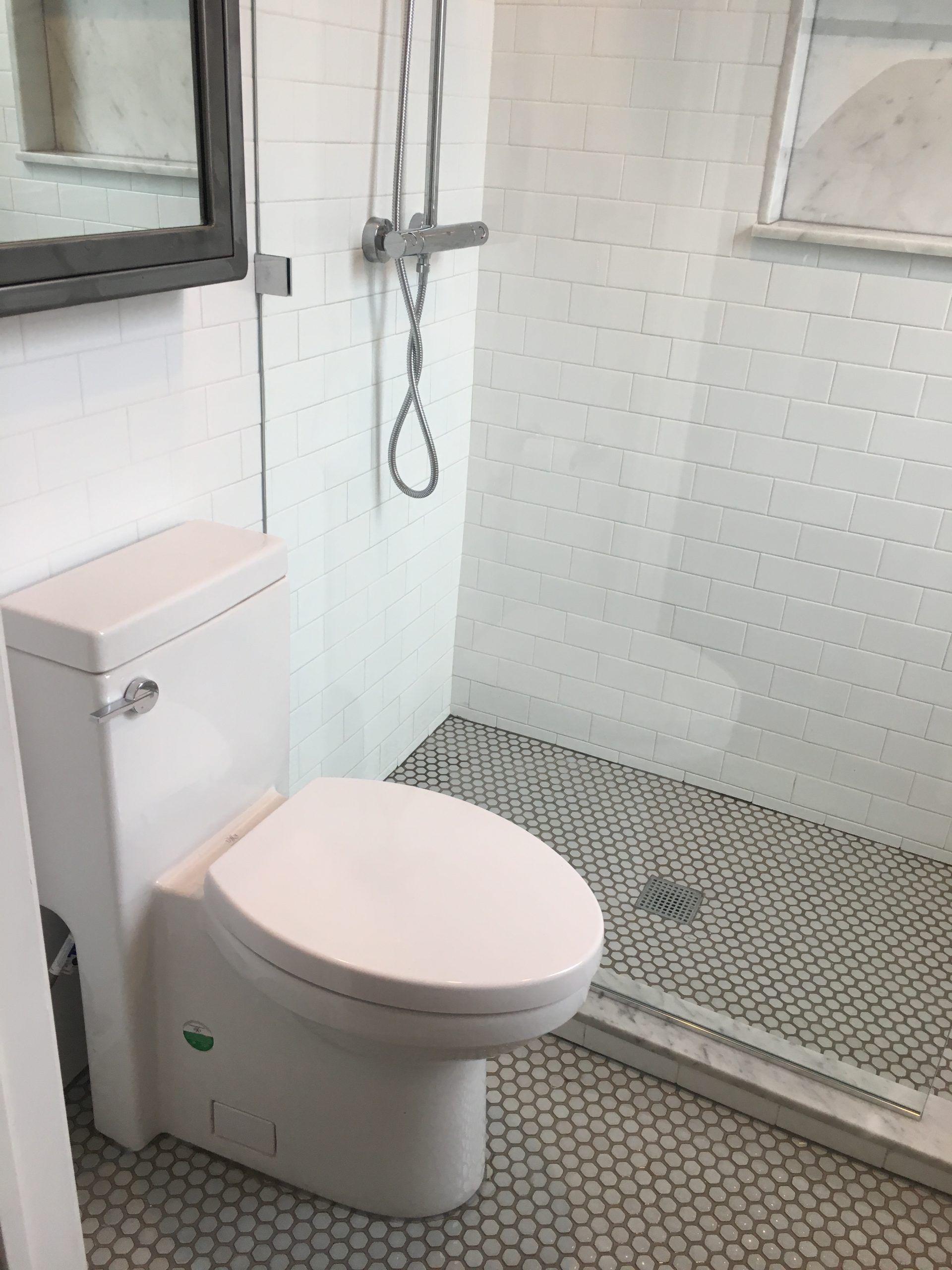 Accessible bathroom with white toilet, tiled shower, and handheld showerhead.