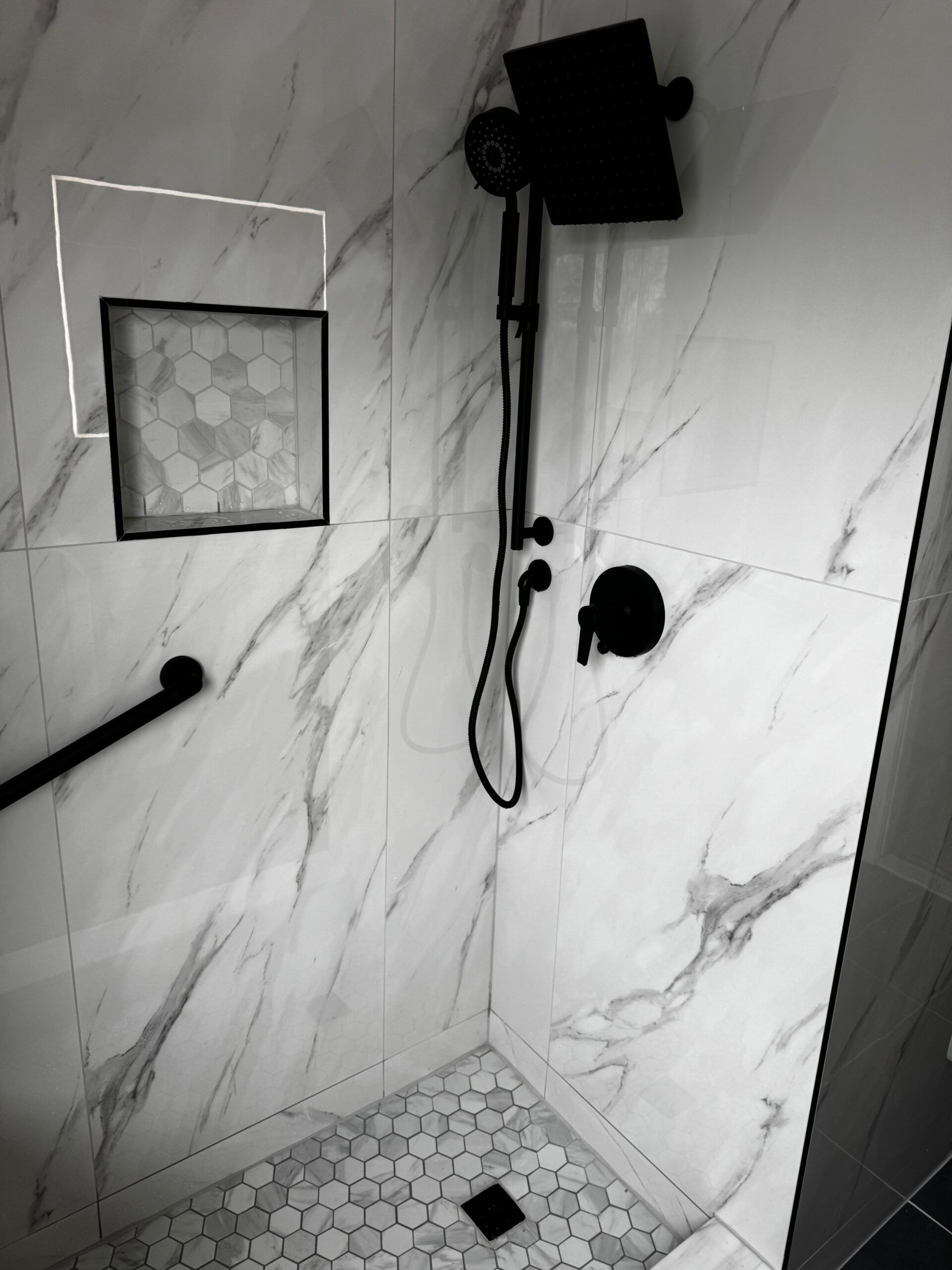 Modern tiled shower with a rain showerhead, hand shower, built-in niche, and drain.
