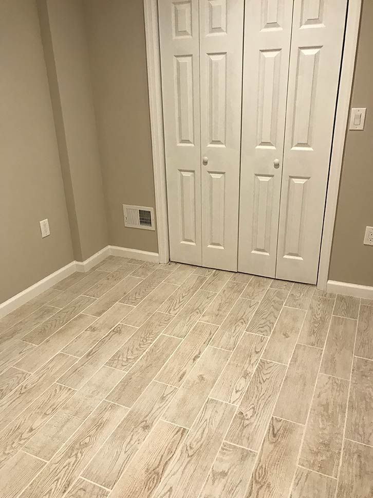 Empty room with beige walls, light wood flooring, and double closet doors near a corner.