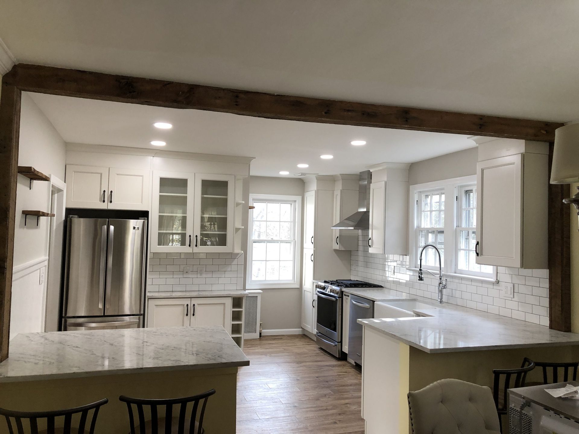 Bright kitchen with stainless steel appliances, white cabinets, and a large island under recessed lighting