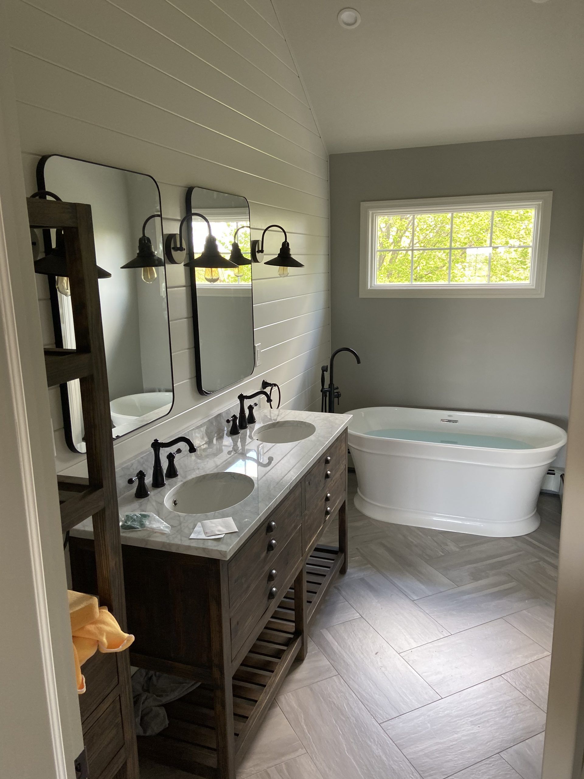 Modern bathroom with double vanity, freestanding tub, and window light