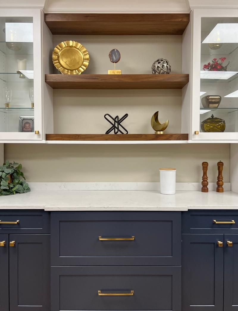 Built-in navy cabinet with wood shelves, brass accents, and white decor in a modern living space